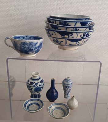 several blue and white bowls and vases are on display in a glass case