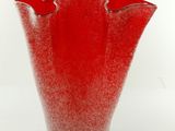 un vase rouge posé sur une surface blanche