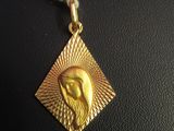 a close up of a gold pendant with a bird on it ' s face