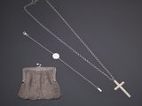 une chaîne en argent avec une croix et une pochette sur fond noir