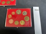 two red boxes with gold coins in them on a table