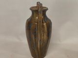 a brown and blue vase sitting on a white surface