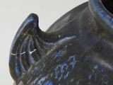 a close up of a blue and black vase on a white surface