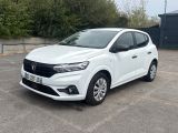 La voiture blanche est garée sur un parking près d'un immeuble.
