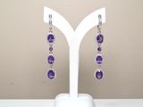 Boucles d'oreilles en améthorate violet et topazte blanc, présentées sur un socle blanc