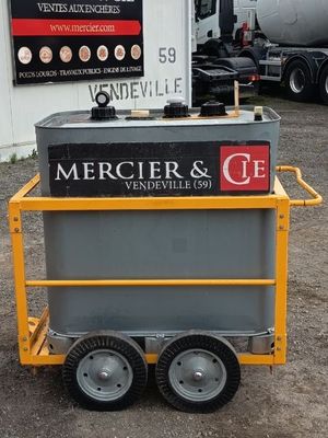 un petit chariot sur lequel est accrochée une pancarte, devant un immeuble