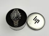 a watch sitting in a metal box on a white surface