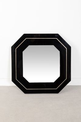 un miroir noir posé sur un sol en béton, près d'un mur blanc