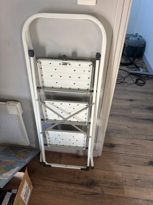 a white folding chair next to a shelf in a room