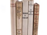 several old books are stacked on top of each other on a white surface