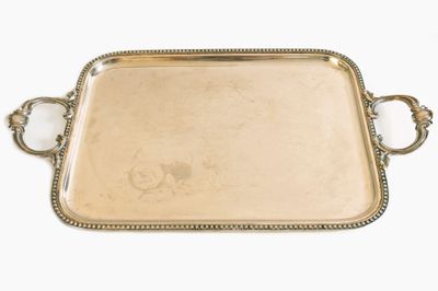 un plateau en argent avec des poignées et des poignées sur une surface blanche