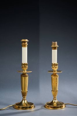 a pair of brass candles with white candlesticks on them