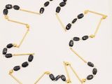 a close up of a necklace on a white surface with black beads