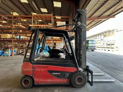 a red forklift in a warehouse with pallets in the background