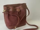 a brown purse with a strap on it sitting on a white surface