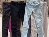 Plusieurs paires de pantalons sont empilées sur un chariot dans un entrepôt