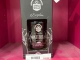une bouteille de whisky vide repose dans une boîte posée sur une surface rose