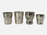 trois verres à shot en argent posés les uns à côté des autres sur une surface blanche