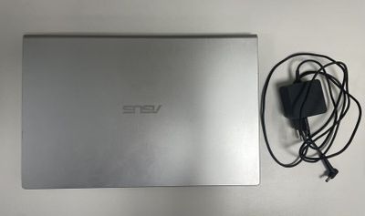 un ordinateur portable ouvert posé sur une table à côté d'un chargeur