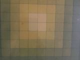 a bathroom with a toilet and a tiled wall