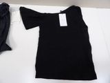 a black t - shirt on a bed next to a pair of pants