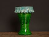a green vase sitting on a table with a black background