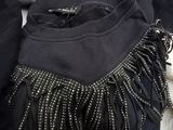 a black purse with a fringe on it sitting on a bed