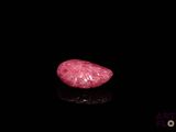 a close up of a pink diamond on a black surface