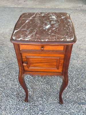 an old wooden table with a marble top on a gravel ground