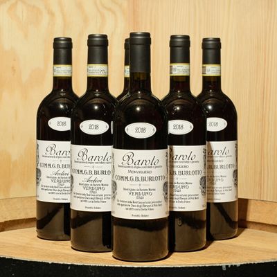 six bottles of wine are lined up on a barrel