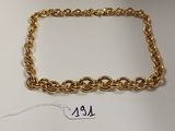 gros plan d'un bracelet en chaîne en or sur une surface blanche