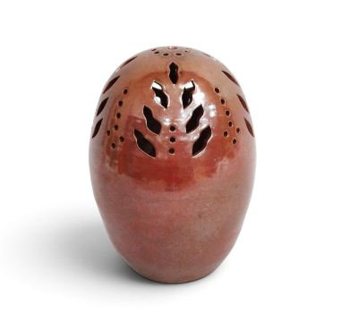 a red vase with holes in it on a white surface