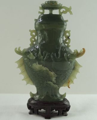 un vase vert orné d'un dragon, posé sur une table