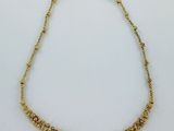 un collier en or orné de petites perles sur fond blanc