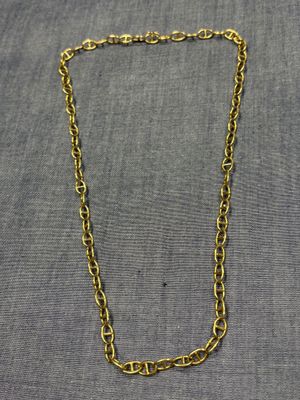 un collier à chaîne en or posé sur un tissu gris