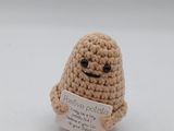 a small stuffed animal holding a sign on a white surface
