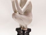 a statue of a woman kneeling on top of a black and white base