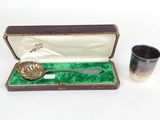 a silver spoon in a case next to a silver cup