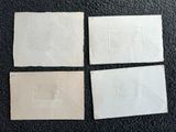 quatre feuilles de papier blanc posées sur une surface noire