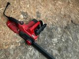 un ventilateur rouge posé par terre, muni d'une poignée noire
