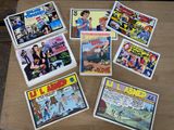 Plusieurs bandes dessinées sont posées sur une table au plateau en bois.