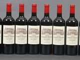 six bottles of red wine lined up in a row on a table