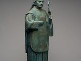 statue en bronze représentant un prêtre tenant un bâton et une croix