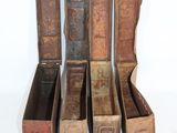 several old books are lined up in a row on a white surface