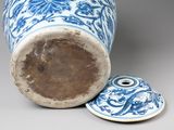 a blue and white vase with a lid next to it