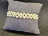 un gros plan d'un bracelet de perles blanches posé sur un oreiller