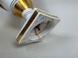 a close up of a white and gold vase on a table