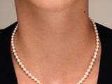 un gros plan d'une femme portant un collier de perles