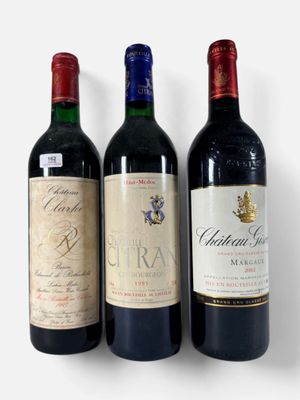 trois bouteilles de vin sont alignées sur une surface blanche