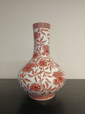 a red and white vase sitting on a black table